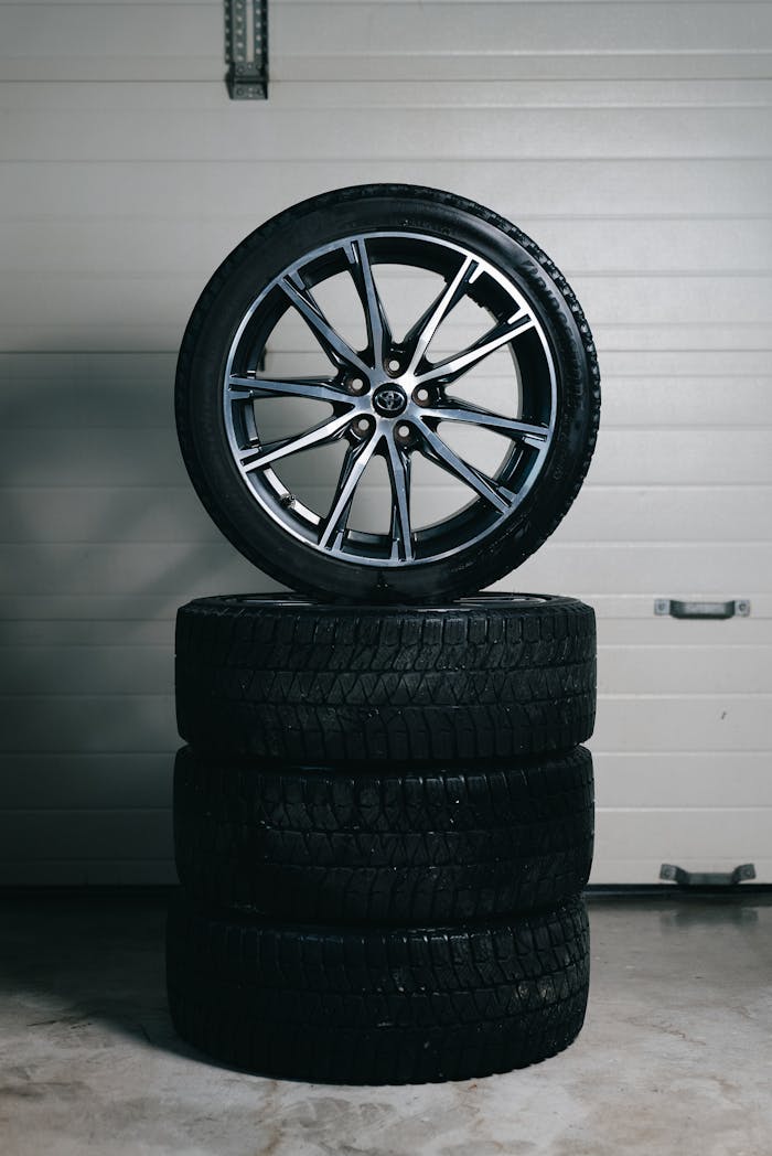 Car tires stacked with an alloy wheel on top in a garage setting. Perfect for automotive themes.
